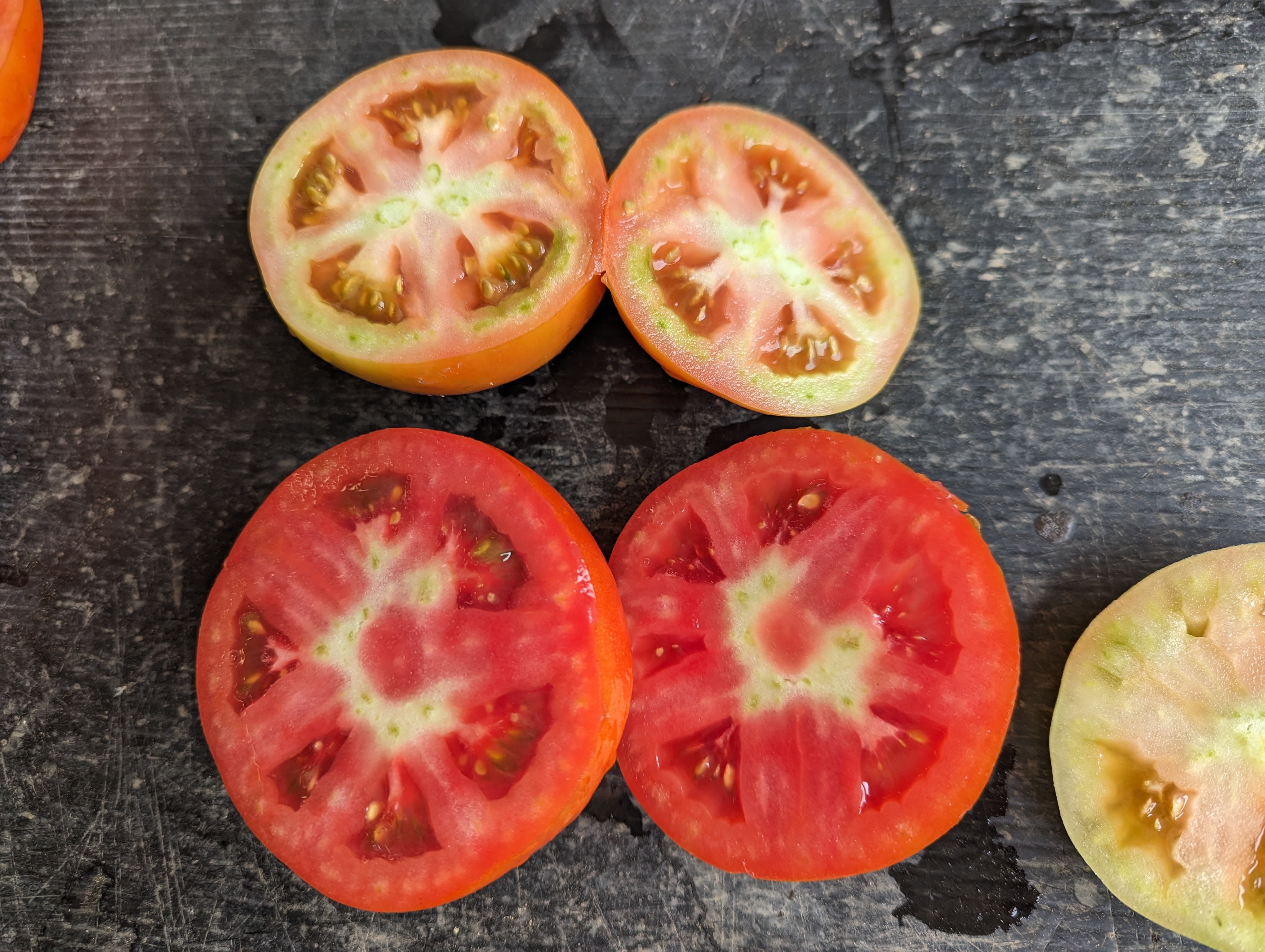 Tomatoes cut in half showing internal white tissue.